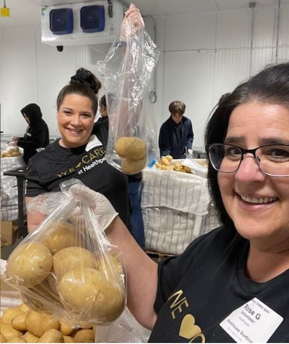 Two women holding bags of potatoes