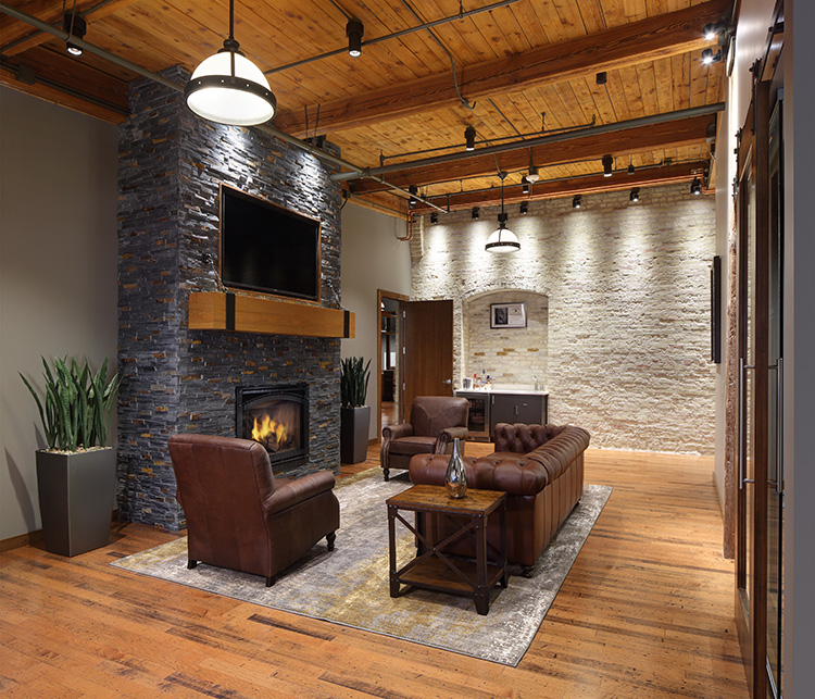 A sofa and chairs in an office with a TV above a fireplace