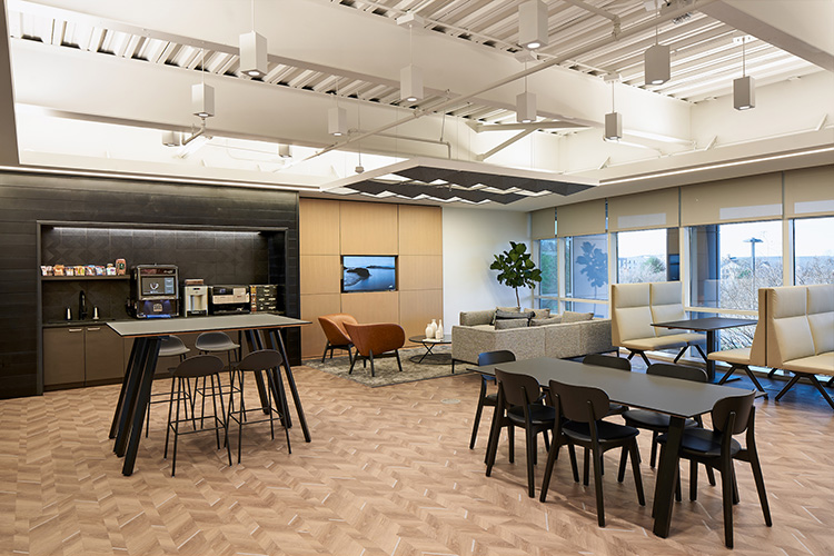 An office break room with tables, chairs, a TV, and a coffee machine