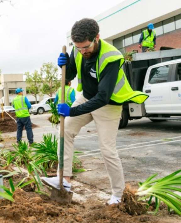 Man in a safety jacket digging a hole with a shovel