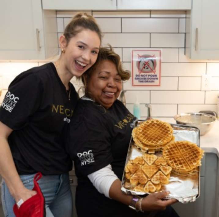 Two women holding a tray of waffles
