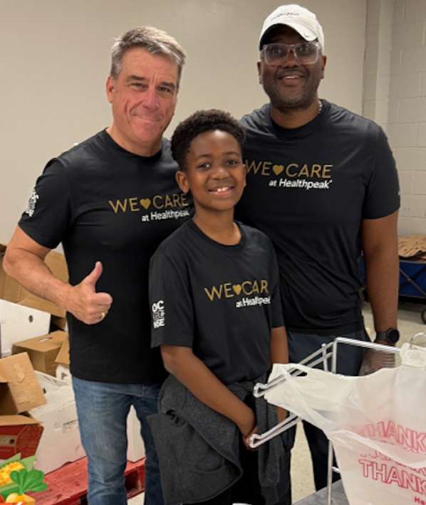Three people with We Care at Healthpeak shirts smiling